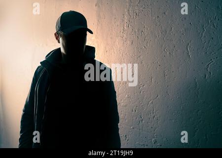 Krimineller, verdächtiger Fremder oder Stalker. Person mit Gesicht im dunklen Schatten. Anonymer Mann, Terrorverdächtiger oder Gangster-Silhouettenfigur. Stockfoto