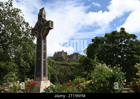 Das Schloss Edinburgh von der Princes Street aus gesehen mit einem keltischen Kreuz, das vor Schottland steht. Stockfoto