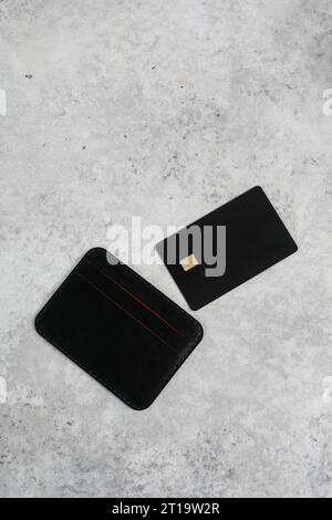 Kartenhalter aus Leder mit leerer schwarzer Karte, isoliert. Schwarze Kreditkarte auf dem Bürotisch. Flache Lagen. Premium-Banking-Konzept. Logo-Design Stockfoto