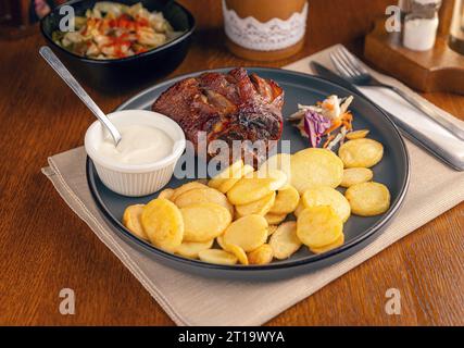 Knusprig gegrillter Schinken mit Pommes frites und Sauce. Gebratene Schweinshaxe mit Kartoffeln Stockfoto