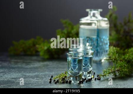 Blaue Gin- und wacholderzweige auf einem Vintage dunkelblauen Tisch. Gin mit wacholderbeeren. Kopierbereich. Stockfoto