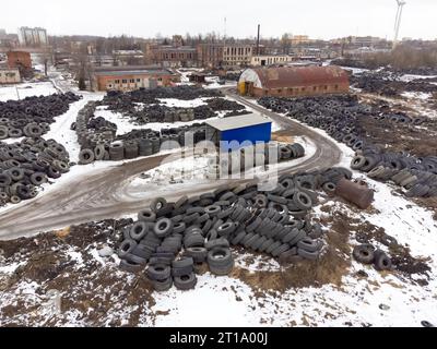 Blick von der Drohne auf eine große Anzahl alter, gebrauchter Reifen im Lager im Winter. Konzept des Recyclings von Altreifen Stockfoto