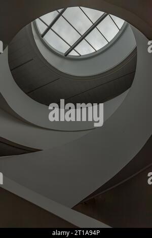 Blick in den Himmel durch den modernen Kanal, runde Decke mit Wendeltreppe. Die weiße Decke mit riesigen transparenten runden Glasscheiben Stockfoto