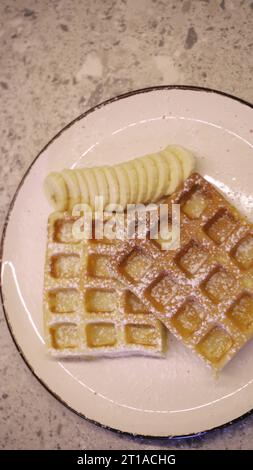 Weiche belgische Waffeln mit Schokoladenbelag beträufeln, während Dessert zubereitet wird. Machen Sie Süßigkeiten aus weichen Waffeln und süßem Eis Stockfoto