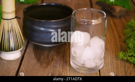 Der Barista gießt Matcha-Grüntee mit Milch und Eis in ein Glas. Cafe Kellnerin serviert kalten Matcha-grünen Tee an einem Gast am Café-Theke. Die Co Stockfoto