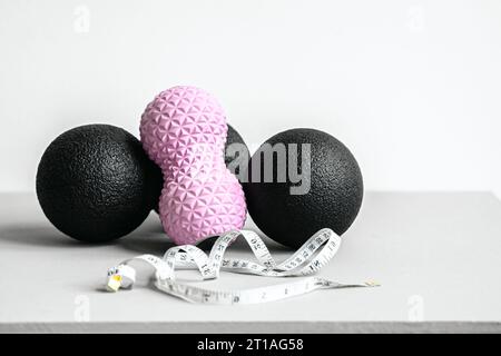 Rosafarbene Erdnusswalze aus Gummischaum, schwarzer Massageball. Yoga, Fitnessgeräte. Zentimeterband zur Messung des Taillenvolumens. Stretching, Pilates Accessori Stockfoto