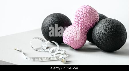 Rosafarbene Erdnusswalze aus Gummischaum, schwarzer Massageball. Yoga, Fitnessgeräte. Zentimeterband zur Messung des Taillenvolumens. Stretching, Pilates Accessori Stockfoto