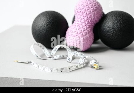 Rosafarbene Erdnusswalze aus Gummischaum, schwarzer Massageball. Yoga, Fitnessgeräte. Zentimeterband zur Messung des Taillenvolumens. Stretching, Pilates Accessori Stockfoto