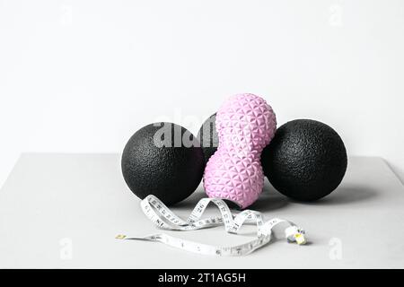 Rosafarbene Erdnusswalze aus Gummischaum, schwarzer Massageball. Yoga, Fitnessgeräte. Zentimeterband zur Messung des Taillenvolumens. Stretching, Pilates Accessori Stockfoto