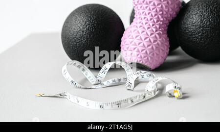 Rosafarbene Erdnusswalze aus Gummischaum, schwarzer Massageball. Yoga, Fitnessgeräte. Zentimeterband zur Messung des Taillenvolumens. Stretching, Pilates Accessori Stockfoto