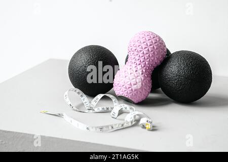 Rosafarbene Erdnusswalze aus Gummischaum, schwarzer Massageball. Yoga, Fitnessgeräte. Zentimeterband zur Messung des Taillenvolumens. Stretching, Pilates Accessori Stockfoto