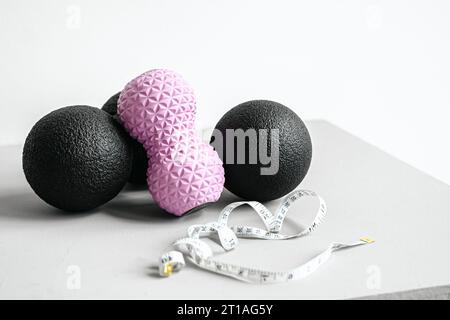 Rosafarbene Erdnusswalze aus Gummischaum, schwarzer Massageball. Yoga, Fitnessgeräte. Zentimeterband zur Messung des Taillenvolumens. Stretching, Pilates Accessori Stockfoto