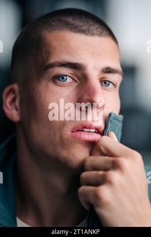 Ein Nahporträt eines hübschen jungen Mannes mit auffälligen grünen Augen, die direkt in die Kamera blicken Stockfoto