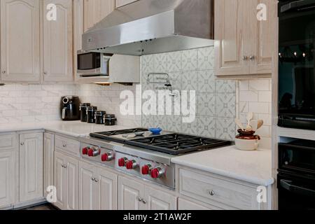 Nachhaltiges modernes Küchendesign mit luxuriösem Gasherd und Airfryer in der Ecke. Topffüller bei minimalem Fliesenrücksplash Stockfoto