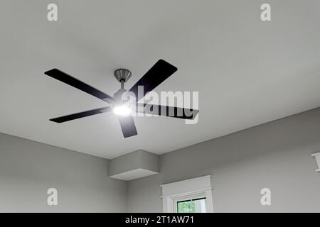 Leuchtender Deckenventilator mit Holzarmen und Chromakzenten an sauberer Decke mit Copyspace Stockfoto