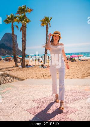 Eine weiße Rothaarige mit Strohhut, die im Sommer am Strand von Calpe, Valencia, spaziert. Spanien Stockfoto