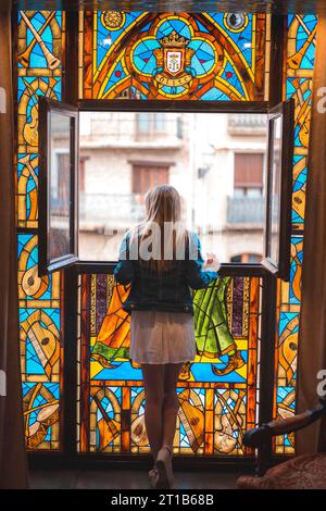 Junge blonde weiße Frau in weißem Kleid und Jeansjacke in einem wunderschönen mittelalterlichen Hotel in der Stadt Olite in Navarra. Spanien, ländlich Stockfoto