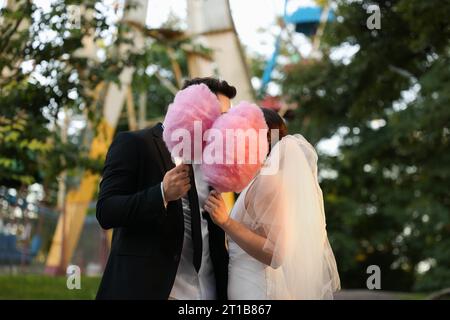 Frisch vermähltes Paar mit rosa Baumwollbonbons draußen Stockfoto