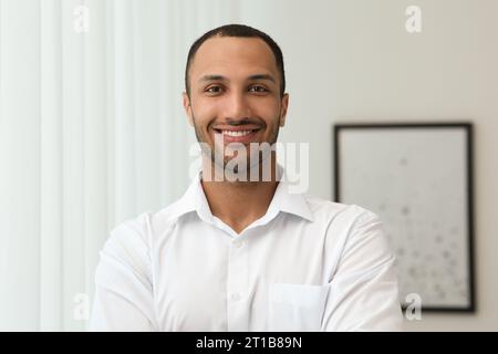 Porträt eines hübschen jungen Mannes in weißem Hemd drinnen Stockfoto