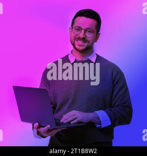 Schöner Mann mit Laptop in Neonlichtern Stockfoto