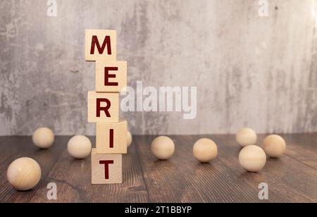 Leistungssymbol. Holzkreise mit dem Wort "Verdienst". Schöner weißer Hintergrund, Kopierraum. Business- und Leistungskonzept Stockfoto