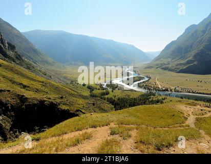 Blick von der Spitze des malerischen Tals in die Sonnenstrahlen der aufgehenden Herbstsonne mit einem wunderschönen, sich windenden Fluss, der darunter fließt. Chulyshman River val Stockfoto