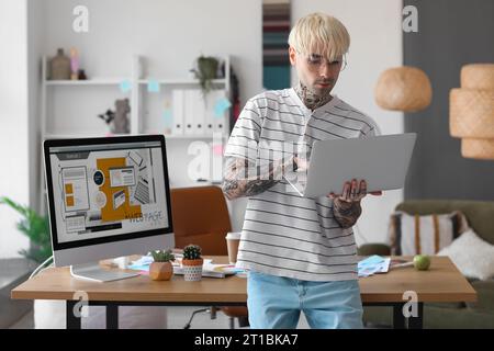 Tätowierter Grafikdesigner, der mit einem Laptop im Büro arbeitet Stockfoto