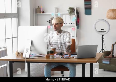 Tätowierter Grafikdesigner, der mit einem Computer am Tisch im Büro arbeitet Stockfoto