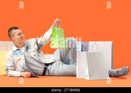 Junger Mann mit Einkaufstaschen auf rotem Hintergrund Stockfoto