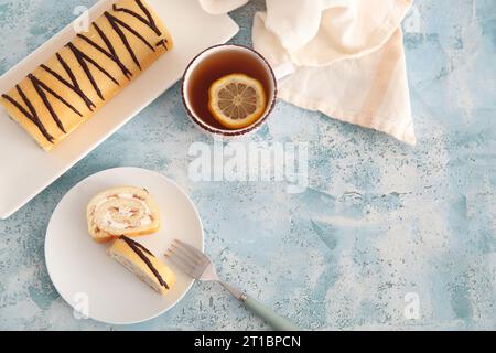 Teller mit süßem Biskuitkuchen und Tasse Tee auf blauem Hintergrund Stockfoto