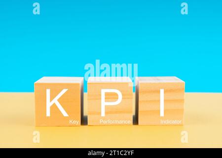 KPI : Key Performance Indicator in Holzwürfeln auf gelbem und blauem Hintergrund. Konzepte für Geschäftsziele. Stockfoto