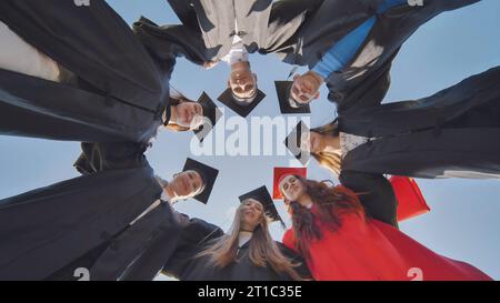 College-Absolventen im Kreis umarmen sich gegenseitig. Stockfoto