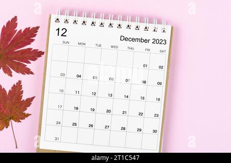 Dezember 2023 Schreibtischkalender für 2023 Jahre mit Herbstahornblatt auf rosafarbenem Hintergrund. Stockfoto