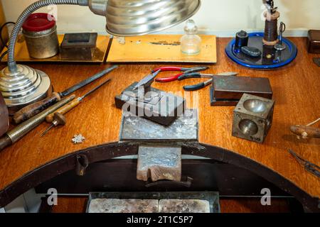 Handwerksplatz eines Juweliers. Schmuckwerkzeuge und -Ausrüstung auf einem Holztisch des Goldschmieds. Stockfoto