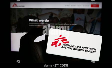 Person mit Handy mit Logo der Wohltätigkeitsorganisation Ärzte ohne Grenzen vor der Webseite. Schwerpunkt auf dem Display des Telefons. Stockfoto