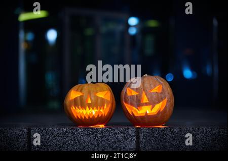 Zwei leuchtende Halloween Kürbisse in der Stadt in der Nacht. Erzünde die Stadt nachts, Bokeh Stockfoto