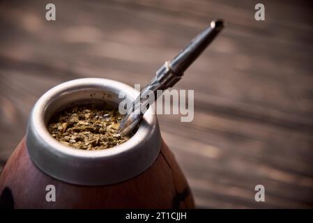 Yerba Mate in Kalabash auf dunklem hölzernem Hintergrund. Stockfoto