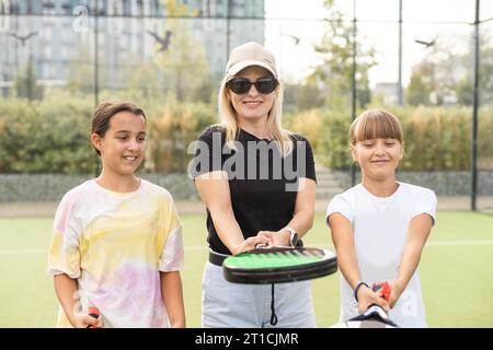 Aktive junge Frau, die Padel Tennis mit einer Gruppe von Spielern auf dem Tennisplatz im Freien übt Stockfoto