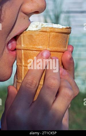 Kind beißt in der Natur eine Waffeltasse mit Pistazieneis Stockfoto