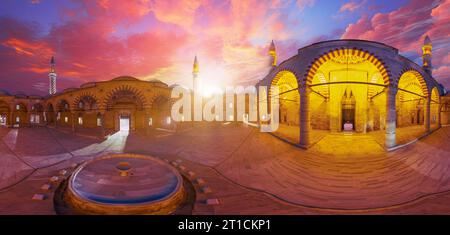 360-Grad-Blick auf den Innenhof der UC Serefeli-Moschee von Edirne in der Türkei. Elegante Minarette und komplizierte Bögen werden von Sonnenuntergang wunderschön beleuchtet Stockfoto