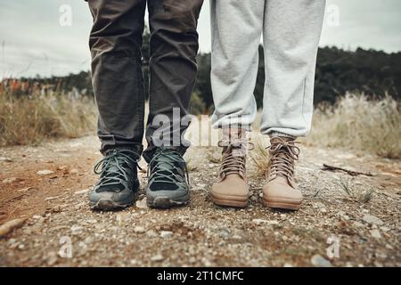 Füße, Wandern und Paare auf der Bergstraße mit Reisen, Urlaub und Abenteuer zusammen im Freien. Schuhe, Reise und Klettern in der Natur mit Wandern Stockfoto