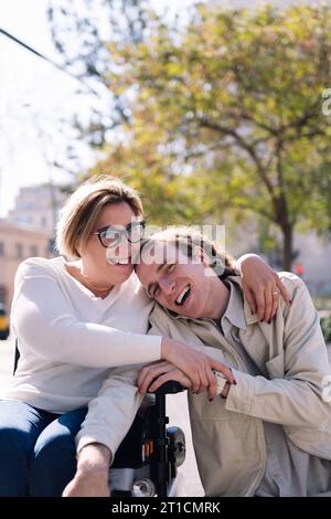 Ein paar Männer und Frauen, die im Rollstuhl lachen Stockfoto