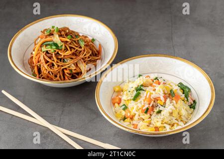 Nudeln mit Gemüse und Reispilaf mit Ei und Mais in einer weißen Schüssel auf dunklem Grund Stockfoto