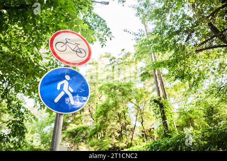 Fahrrad- und Fußgängerschilder im Sommer. Italien. Blick auf ein generisches Schild „Fahrradrennen verboten“ auf einem Fußgängerweg. Das „kein Radfahren“-Zeichen bedeutet, dass die Verwendung von verwendet wird Stockfoto