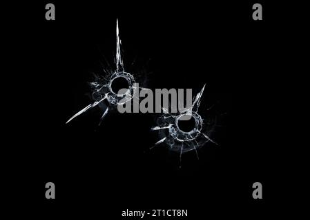 Zwei Kugellöcher im Glas auf schwarzem Hintergrund. Stockfoto