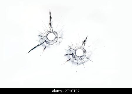 Zwei Kugellöcher im Glas auf weißem Hintergrund. Stockfoto