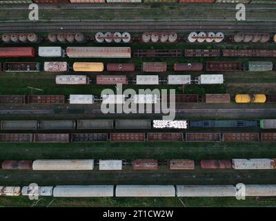 Luftaufnahme eines Güterzuges. Bunte Güterzüge auf dem Bahnhof. Schwerindustrie. Draufsicht von der fliegenden Drohne Stockfoto