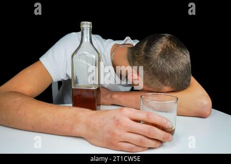 Autoschlüssel und Alkohol auf dem Tisch. Betrunkener Mann, der auf dem Tisch mit einer Flasche Whiskey und Drink schläft. Alkoholismus. Fahren Sie nicht, wenn Sie betrunken sind. Stockfoto