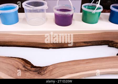 Prozessfertigung eines Kunstharz- und Holztisches. Flüssiges Epoxid wird in eine Form mit Holzrohlingen gegossen. Nahaufnahme Stockfoto