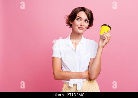 Foto von Managerin, die Kaffee zum Mitnehmen nach Hause bringt und eine Papiertasse hält, die leeren Platz für Preise auf rosafarbenem Hintergrund aussieht Stockfoto